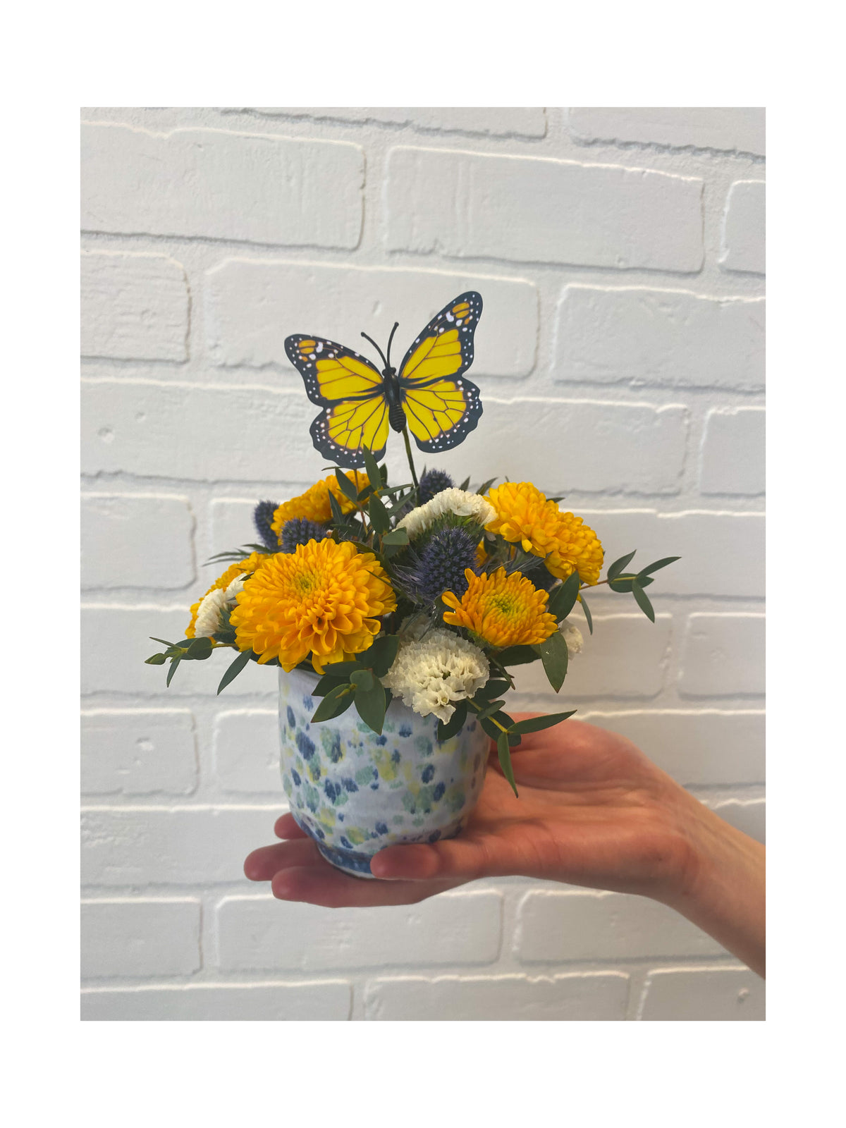 Small floral arrangement with blue, white and yellow.