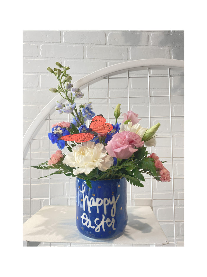An Easter themed arrangment with pink, blue and white flowers.