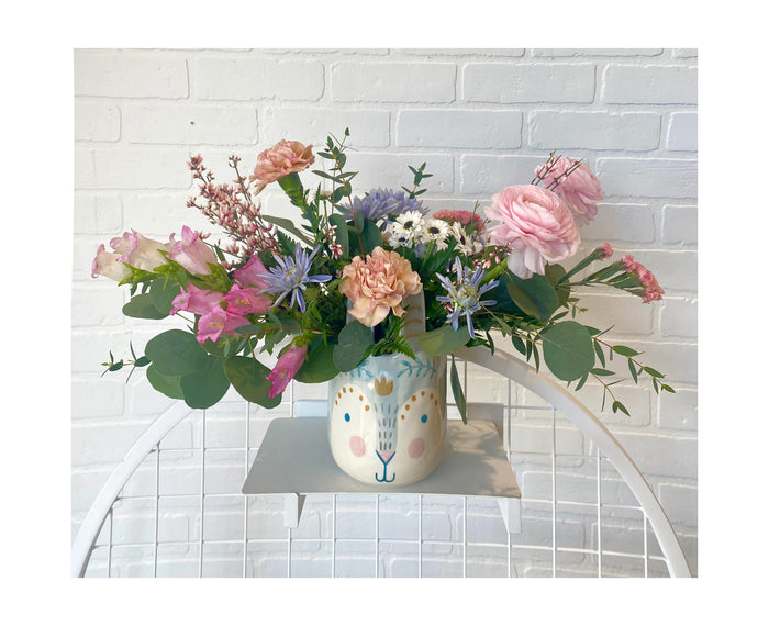 An Easter flower arrangement with light blue, pink and white flowers.
